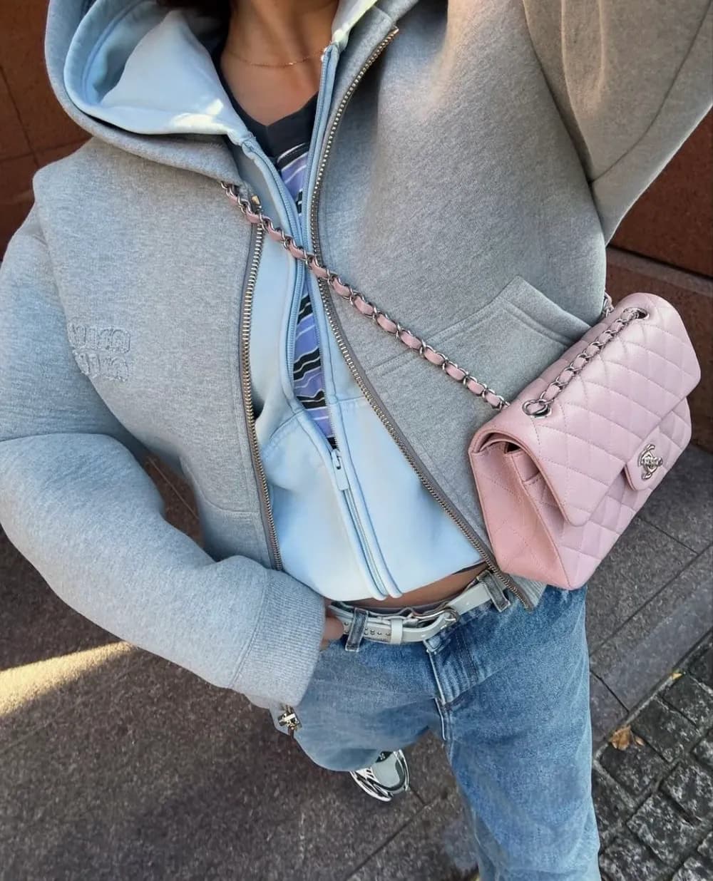 Grey zip hoodie with a pink quilted flap bag and blue jeans